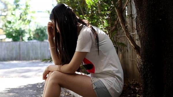 Girl sitting with head in hands.
