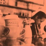 Coffee cups with a cafe worker in background red tinted image
