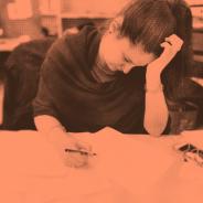 Distressed woman with hand on head holds a pencil in other hand - orange tinted image