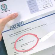 a hand holding a penalty notice, with large letters spelling PAY NOW