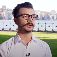 Man with dark hair and a moustache outside looking away from camera