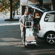 Old man wearing mask pushing a trolley down a street