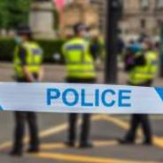 Police tape in front of standing police group