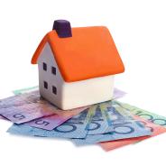 A small model house placed on top of bank notes spread out in fan formation